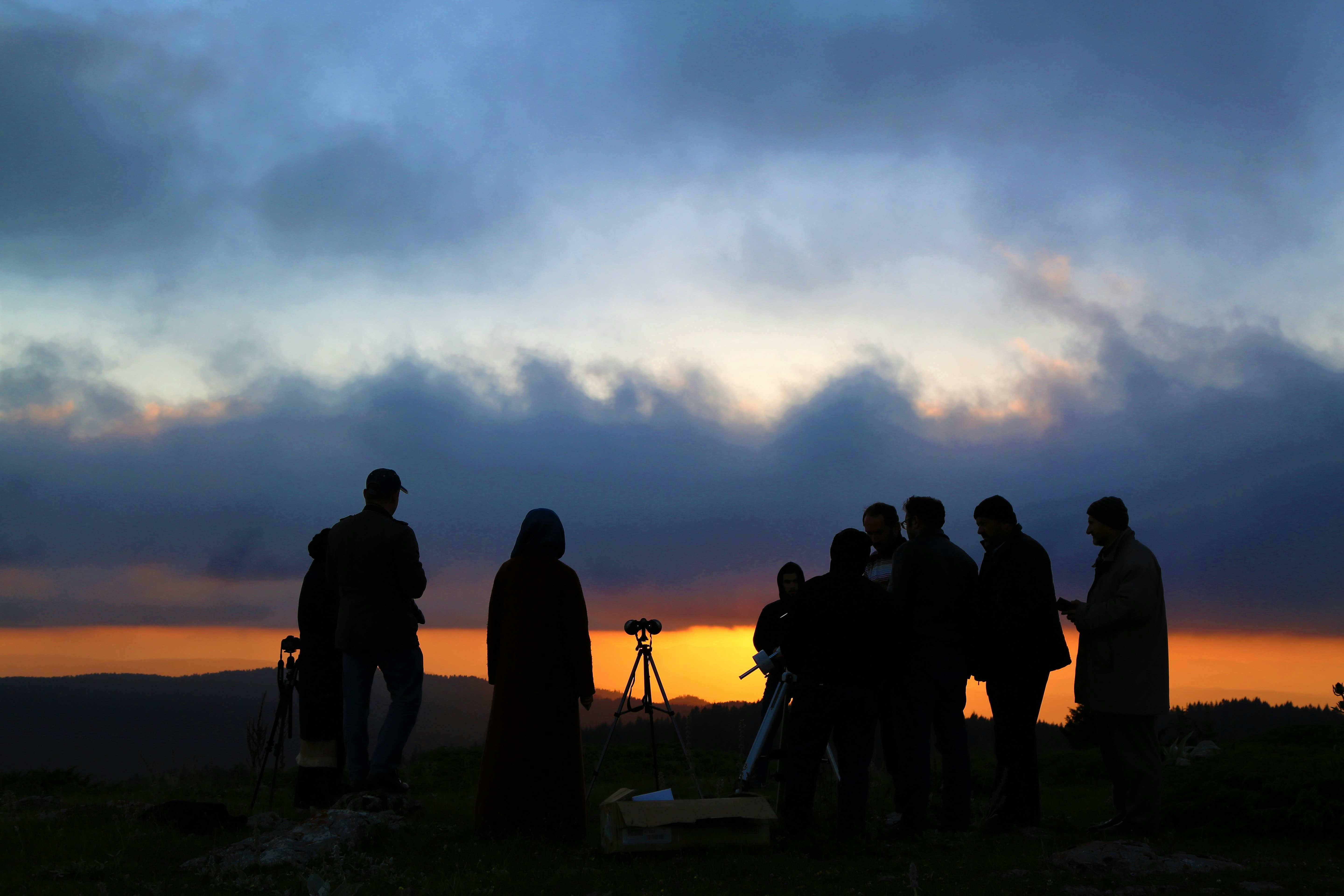 silhouette of people standing on hill during sunset